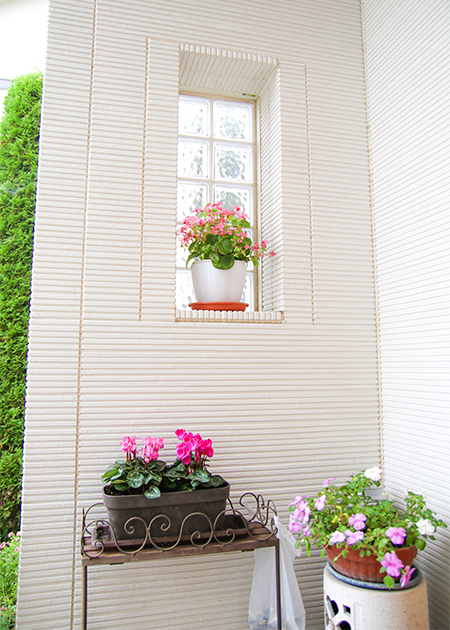 玄関前のガラスブロックは美知子さんのアイデア。西風を防ぐと同時に、鉢植えを置く飾りスペースも設けた